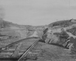 A wide view showing the hole surrounded by remnants of the townsite Photo of the cave-in
