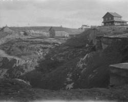 The hole showing the twisted remains of train tracks with a few scattered houses. Photo of cave-in